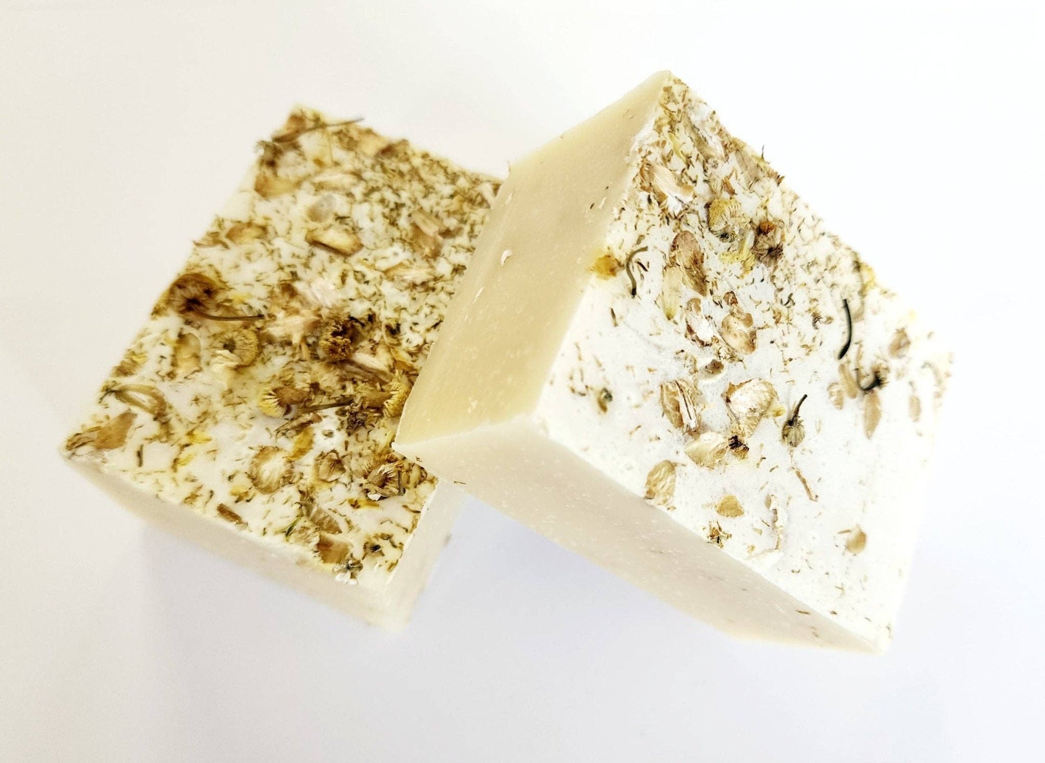 Two pieces of soap with visible ingredients on a white background