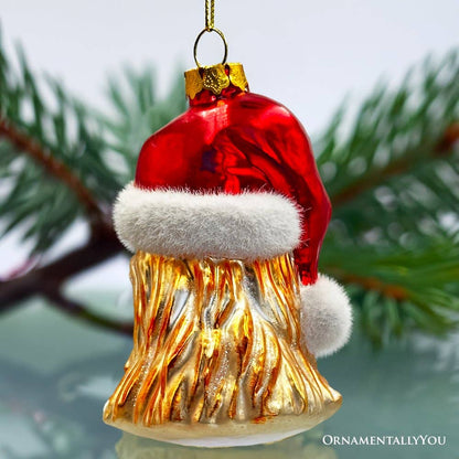 Christmas ornament resembling a gold tree stump with a Santa hat on a blurred green background