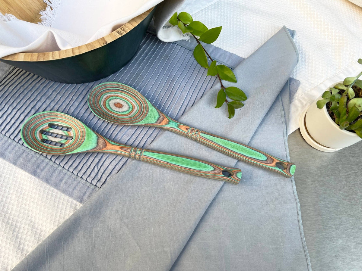 Decorative wooden spoons with green and brown patterns on a gray surface.