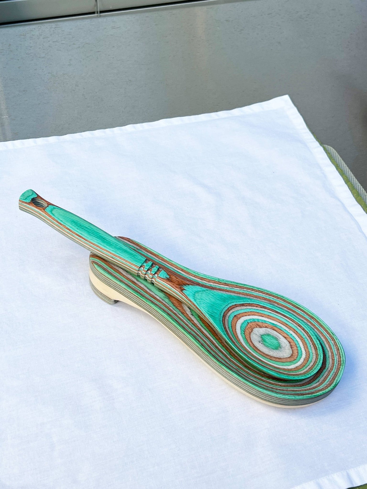 Wooden spoon with green and brown swirl pattern on a white surface