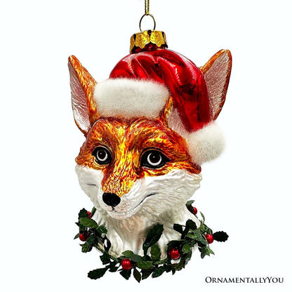 Christmas ornament shaped like a fox head with a Santa hat and holly leaves on a white background.