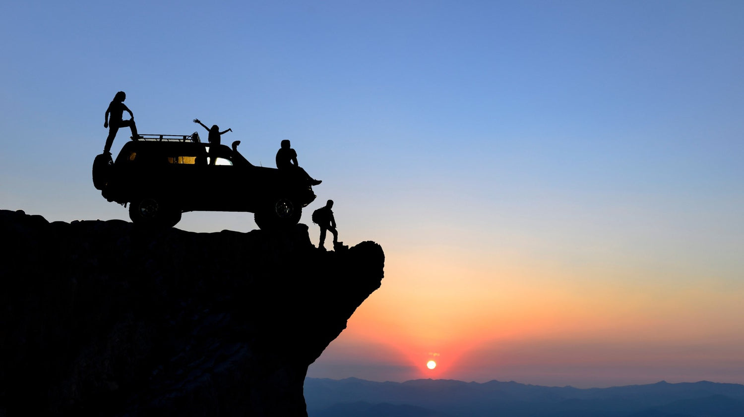 Vehicle on cliff edge at sunset