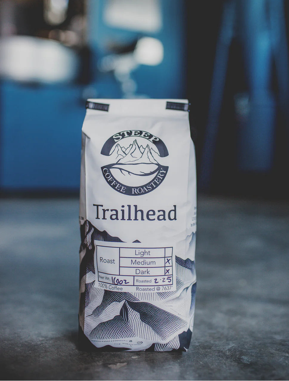 Bag of Trailhead coffee with a blurred blue vehicle in the background
