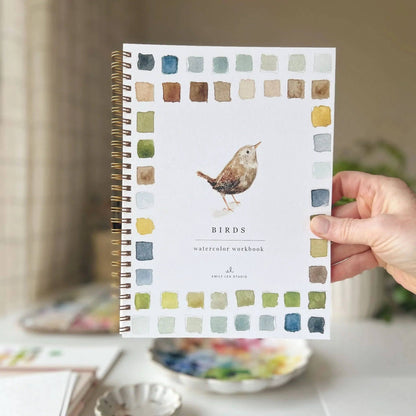 Notebook with bird illustration and color swatches held by a hand on a blurred background