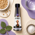 A bottle of Kioke Reserve Tamari Soy Sauce is centered in a styled flat-lay composition with bowls of soybeans, salt, water, and green leaves on a beige and purple background.