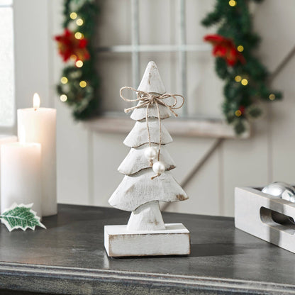 Decorative white Christmas tree figurine on a table with festive background