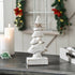 Decorative white Christmas tree figurine on a table with festive background