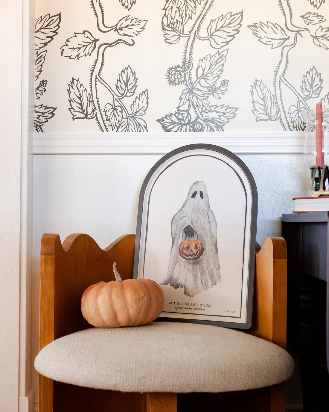 Ghost with pumpkin head print on a serving tray against a decorative wall.