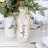 A beige fabric drawstring gift bag with the word &