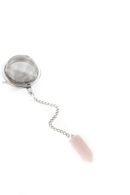 Metallic tea infuser with a pink stone on a white background