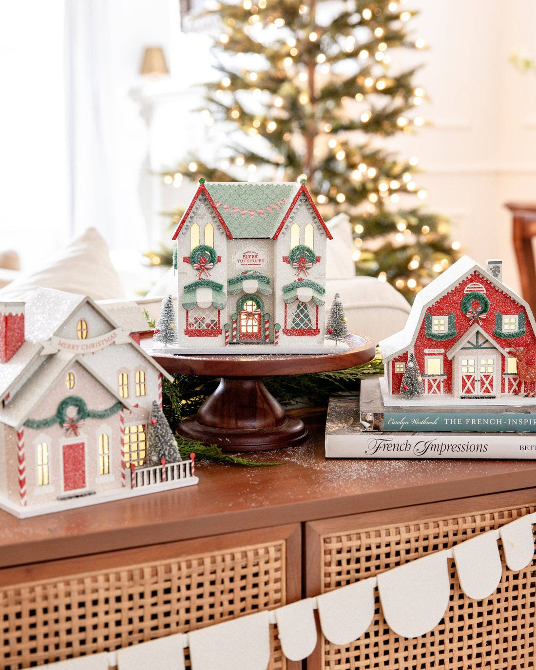 Decorative Christmas houses on a table with a blurred Christmas tree in the background