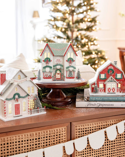 Decorative Christmas houses on a table with a blurred Christmas tree in the background