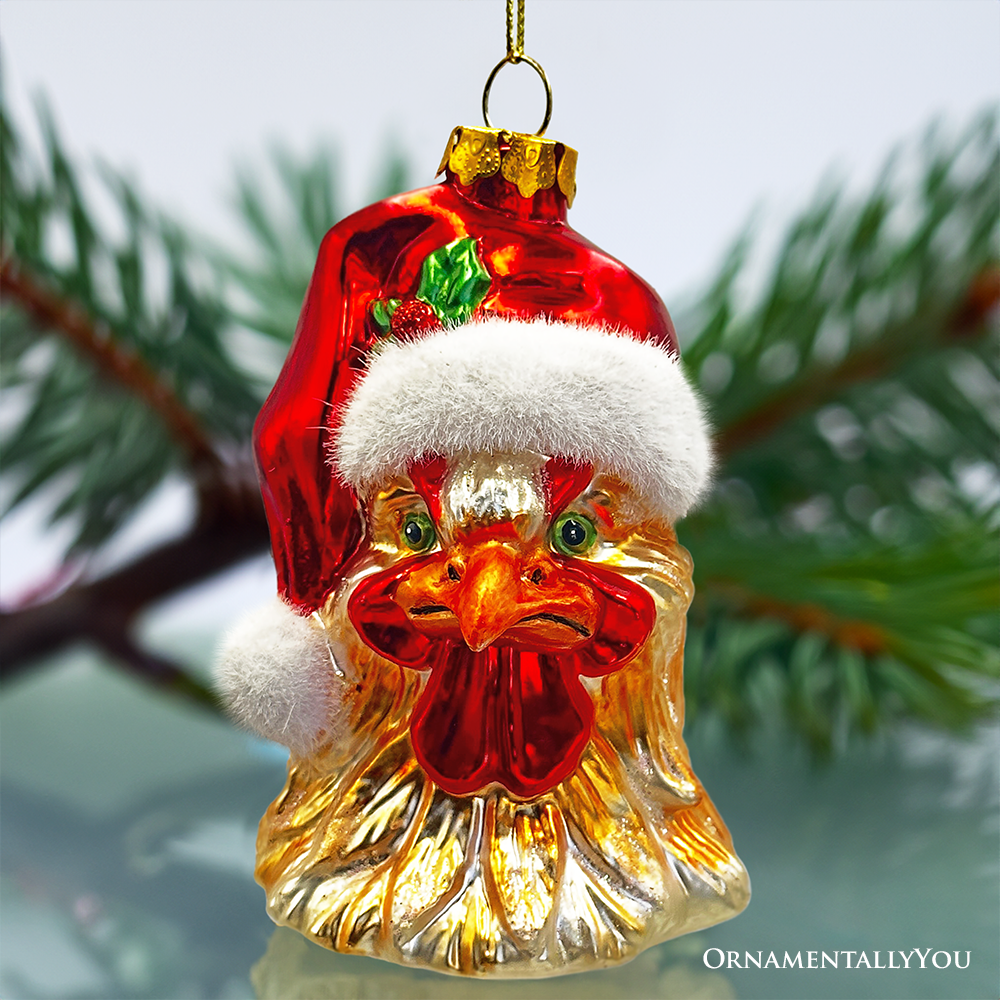Decorative Christmas ornament shaped like a rooster wearing a Santa hat, hanging against a blurred green background.