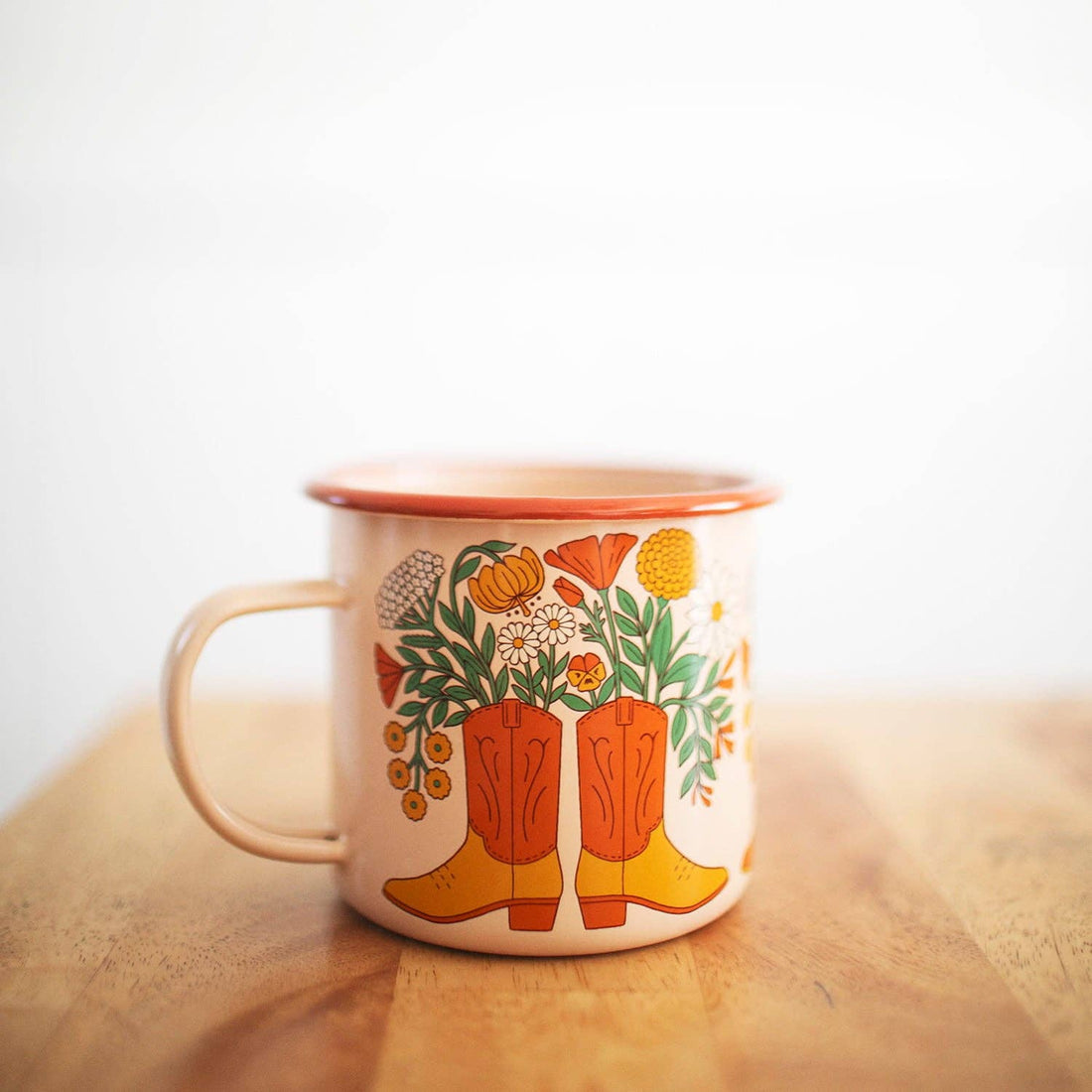 Mug with cowboy boot and floral design on a wooden surface