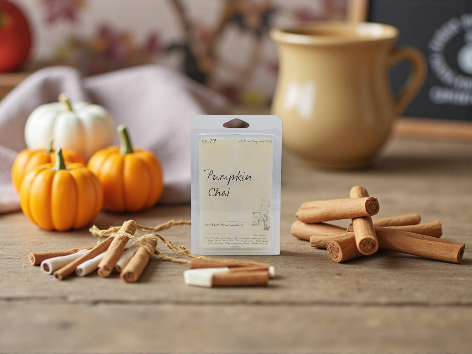 Pumpkin Chai wax tarts package with cinnamon sticks and pumpkins on a wooden surface