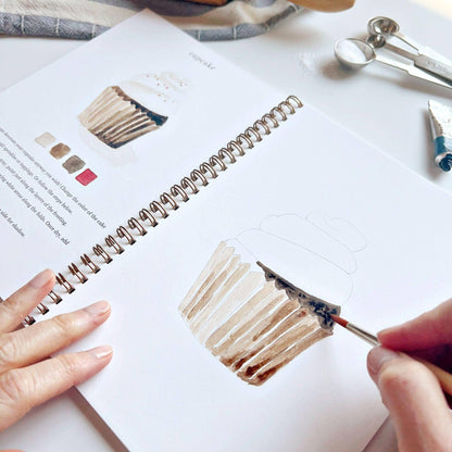 Person painting a color swatch in a sketchbook with a paintbrush