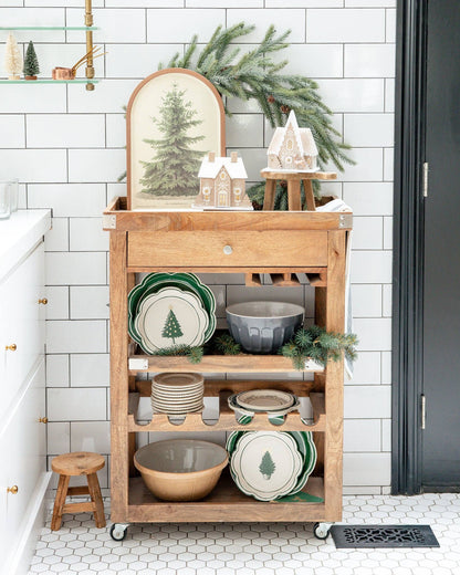 Wooden kitchen cart with festive decor against a white tiled wall.