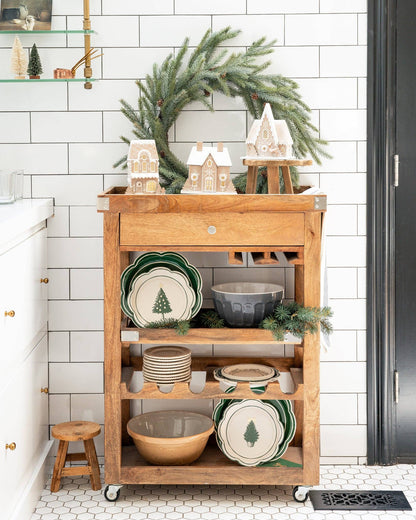 Wooden cart with decorative items in a kitchen setting with a wreath on the wall.