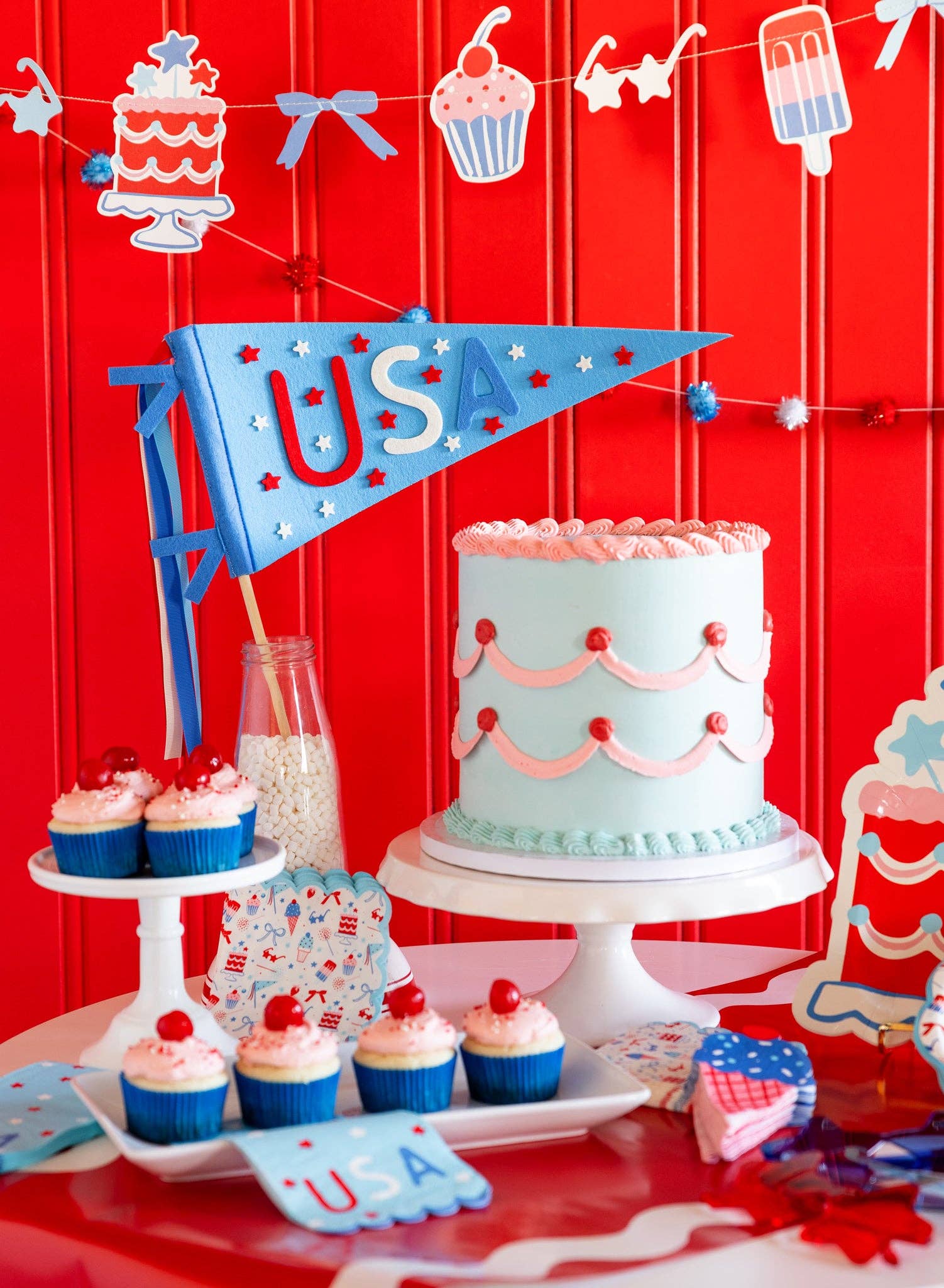 Decorative table setting with a cake, cupcakes, and &