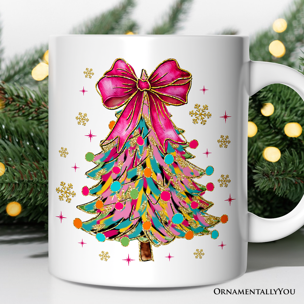White mug with a colorful Christmas tree design featuring a pink bow, surrounded by festive greenery.