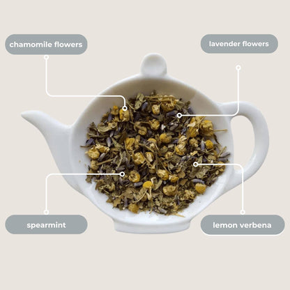Tea infuser with chamomile, lavender, spearmint, and lemon verbena flowers on a beige background