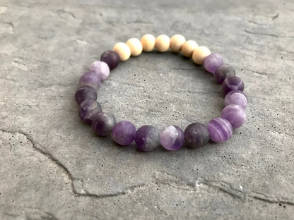 Beaded bracelet with purple and beige beads on a textured surface