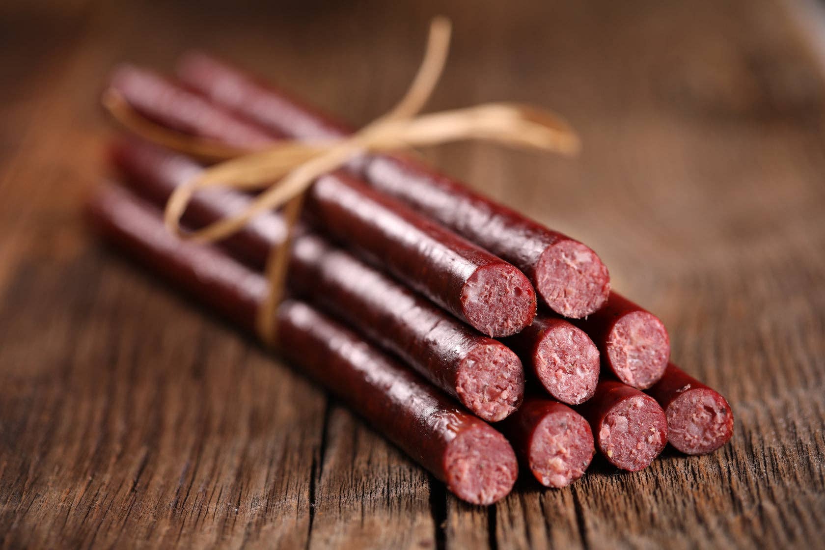 Bunch of beef sticks tied with twine on a wooden surface