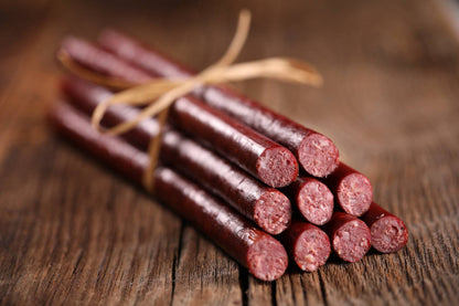 Bunch of beef sticks tied with twine on a wooden surface
