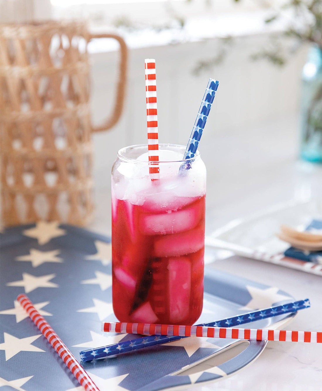 Glass of red iced drink with straws on a tablecloth with star pattern