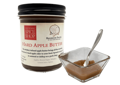 Jar of Old Town Spice Shop Hard Apple Butter with a spoonful in a small dish on a white background