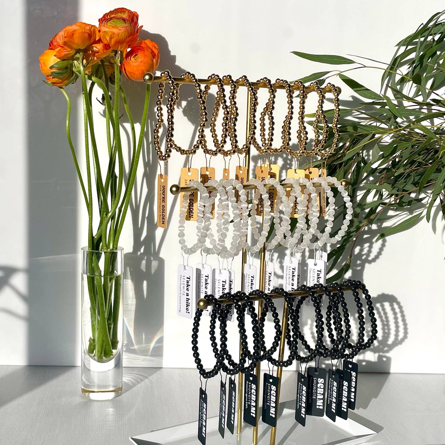 Bracelet display with a vase of flowers on a white surface