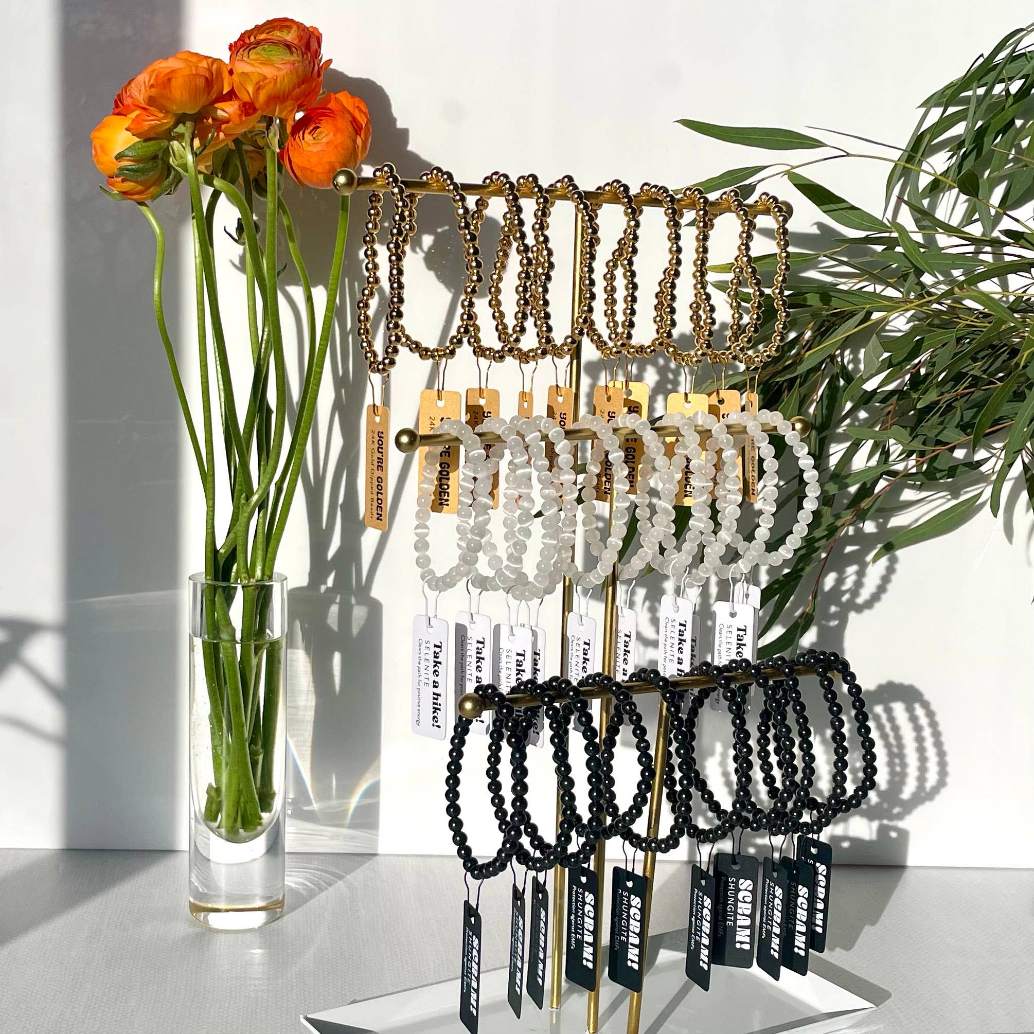 Bracelet display with a vase of flowers on a white surface