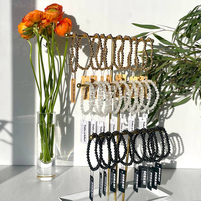 Bracelet display with a vase of flowers on a white surface