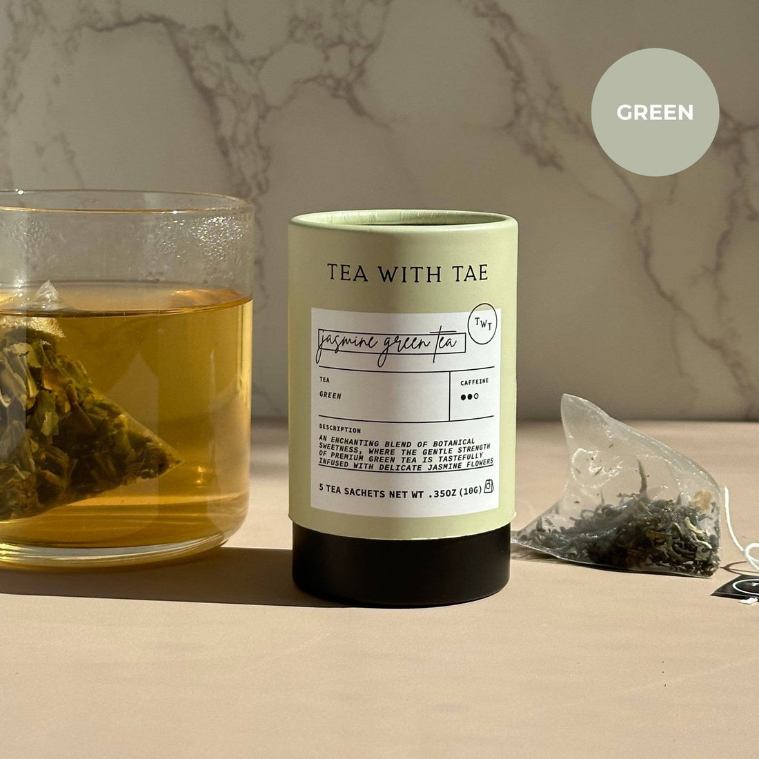 Tea packaging with a glass of tea and tea bags on a marble surface