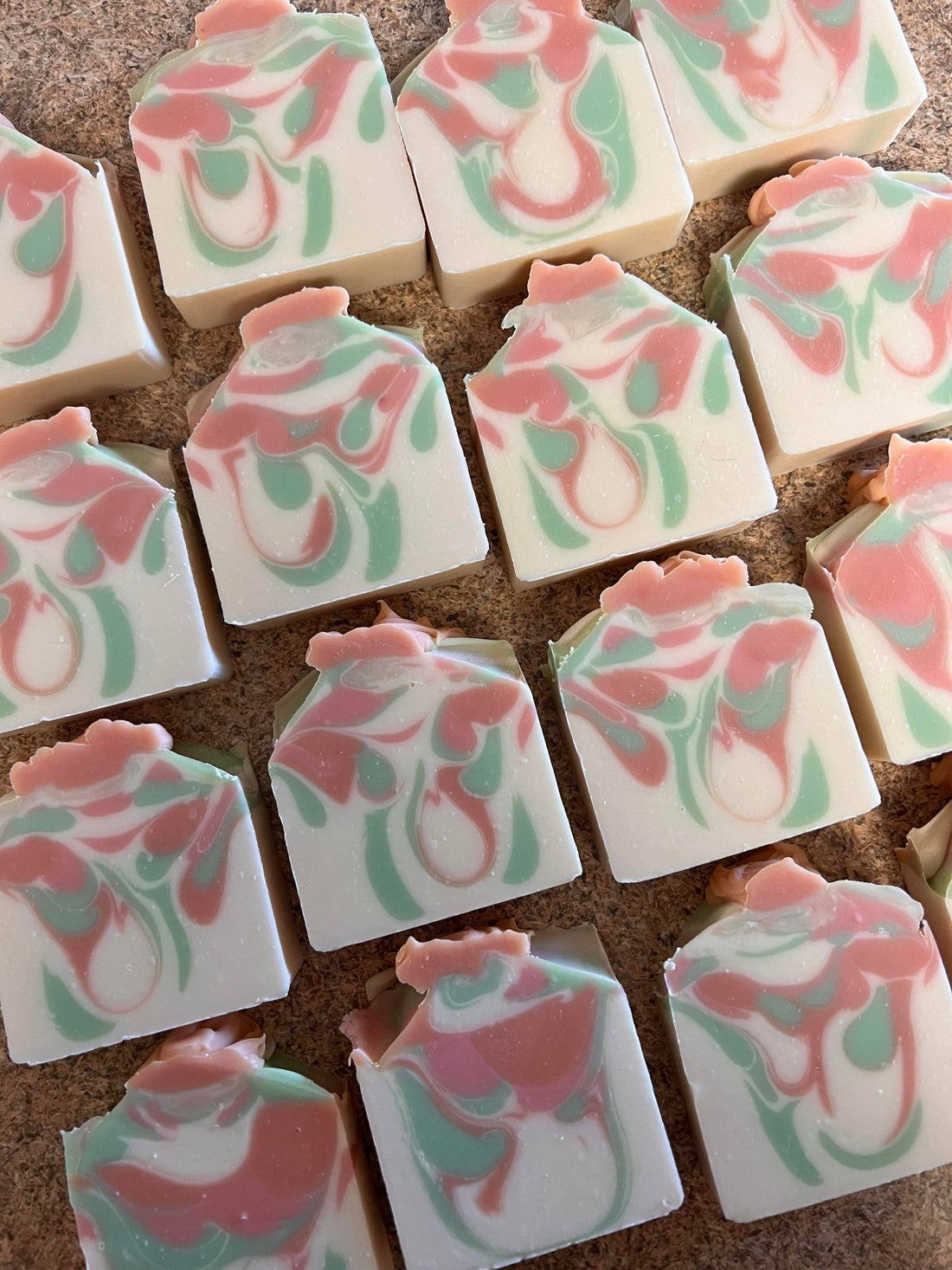 Marble-patterned soap bars with pink and green swatches on a textured surface