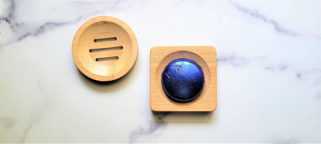 Wooden soap dish with a blue soap bar on a marble surface