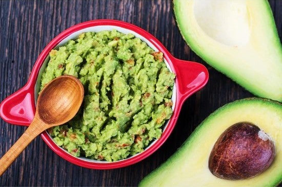 red bowl with guacamole and fresh avocado halves